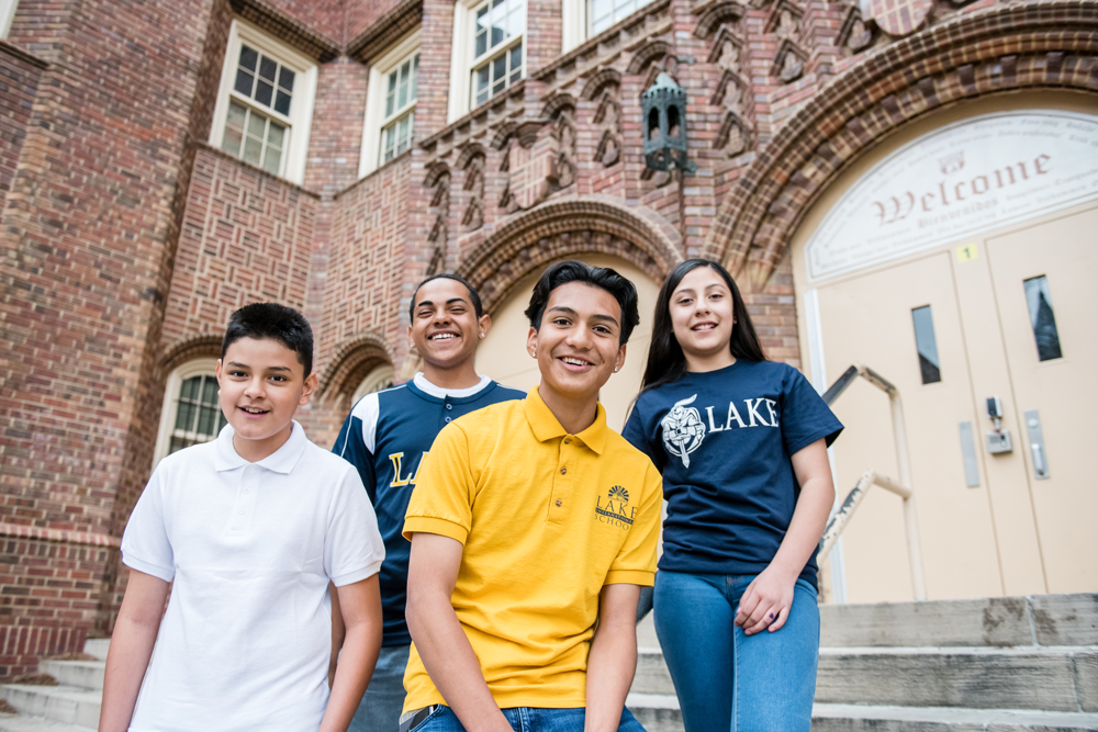 4 students posing in front of school