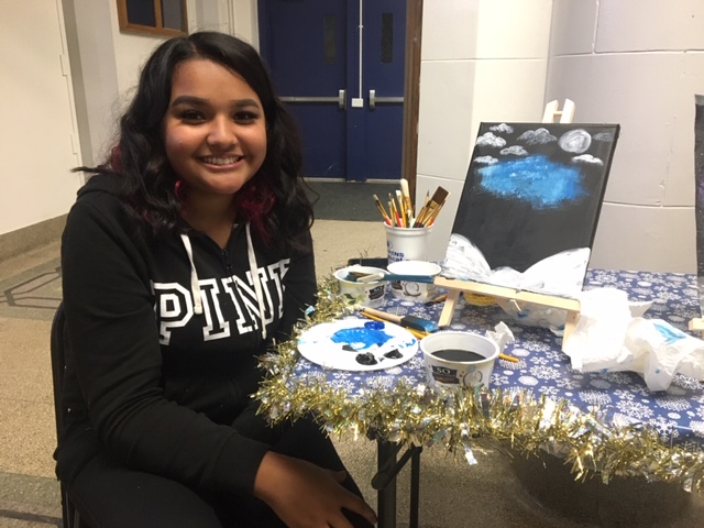 Student posing with cookies and canvas painting