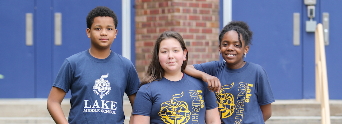 3 students posing in front of school